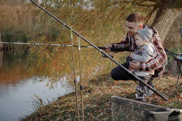 Vater mit kleinem Sohn in der Nähe des Flusses an einem Fischermorgen