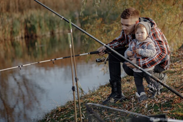 Vater mit kleinem Sohn in der Nähe des Flusses an einem Fischermorgen