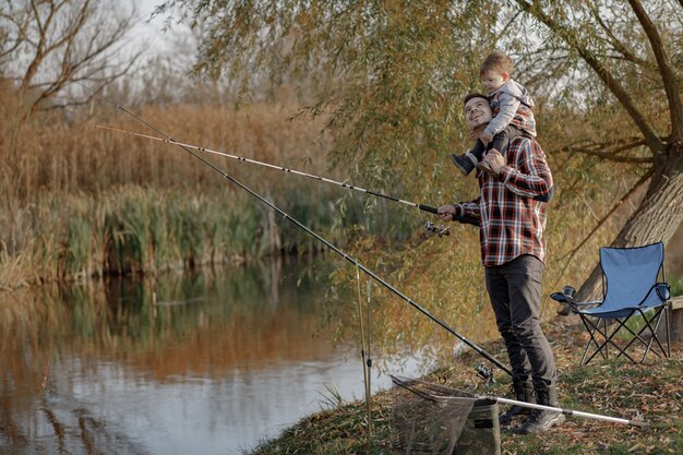 Vater mit kleinem Sohn in der Nähe des Flusses an einem Fischermorgen