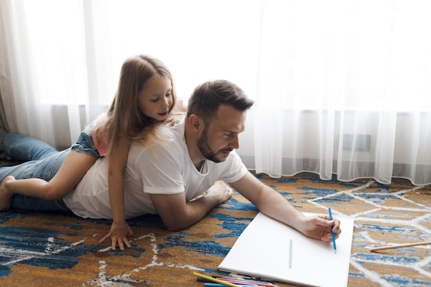 vater mit niedlicher kleiner tochter, die zu hause zeichnet