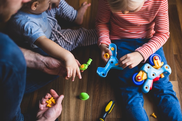 Vater mit seinen Kindern, die die Stücke eines Spielzeugs zusammenstellen