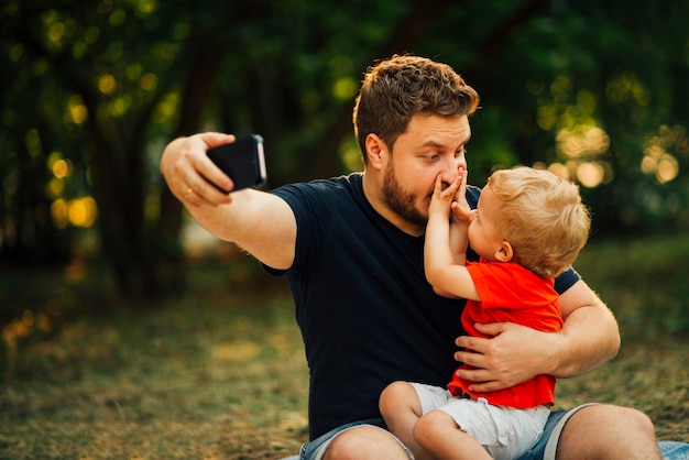 Vater nimmt ein Selfie und spielt mit seinem Kind