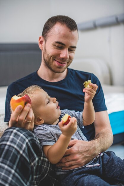 Vater seinen Sohn lächelnd, während Obst essen