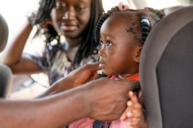 Vater setzt seine Tochter in einen Autostuhl für Kinder