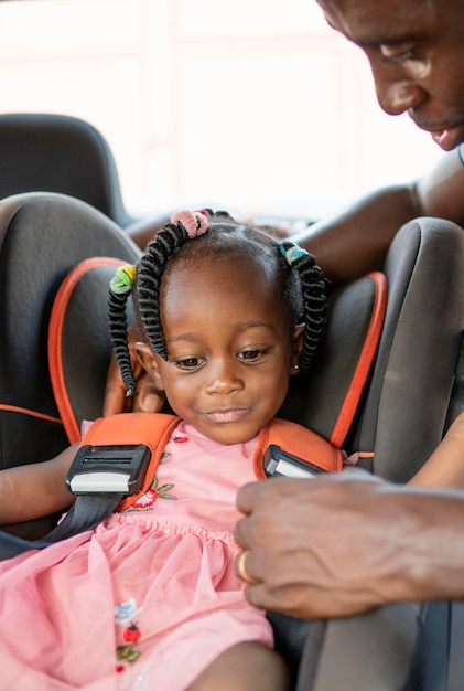 Vater setzt seine Tochter in einen Autostuhl für Kinder