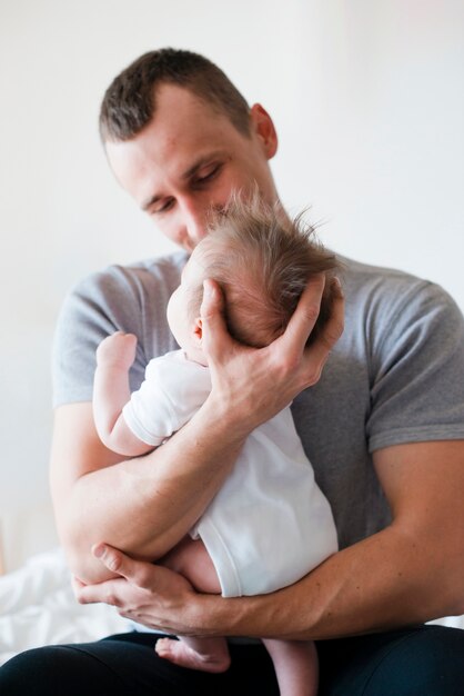 Vater sitzt und umarmt Baby