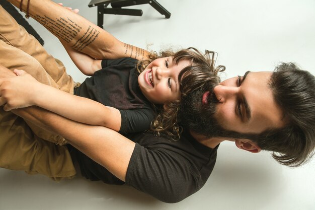 Vater spielt mit dem kleinen Sohn in ihrem Wohnzimmer zu Hause. Junger Vater, der Spaß mit seinen Kindern in den Ferien oder am Wochenende hat. Konzept der Elternschaft, Kindheit, Vatertag und Familienbeziehung.