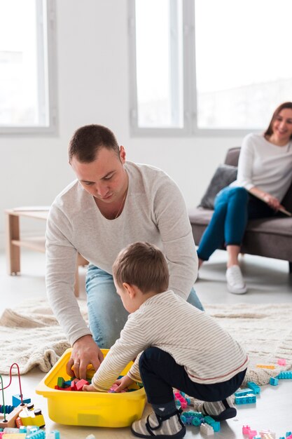 Vater spielt mit Kind, während Mutter zuschaut