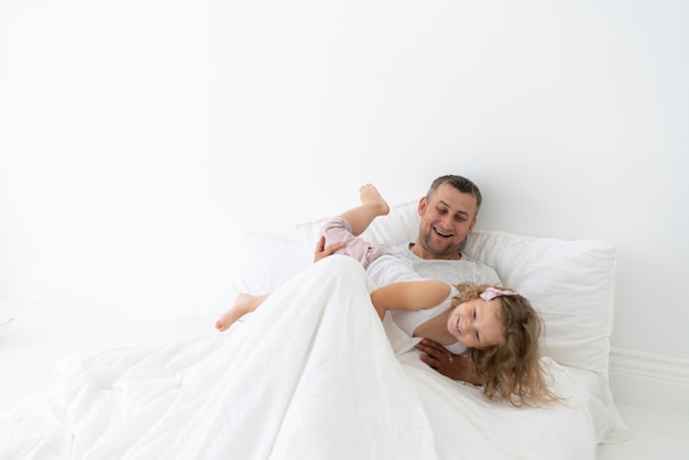 Vater spielt mit Tochter im Schlafzimmer