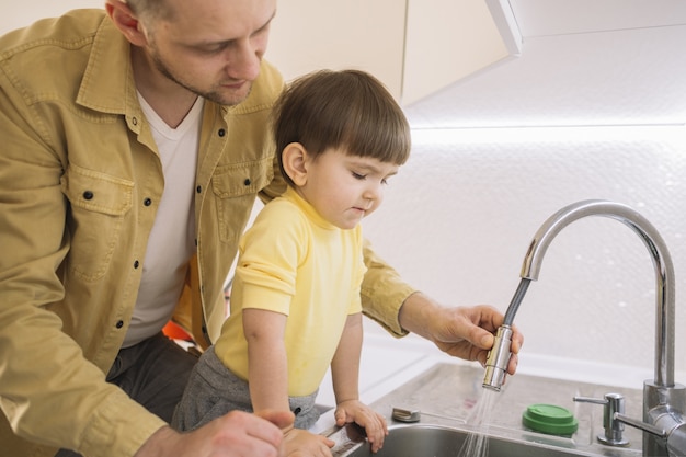 Vater spült das Geschirr und Sohn schaut