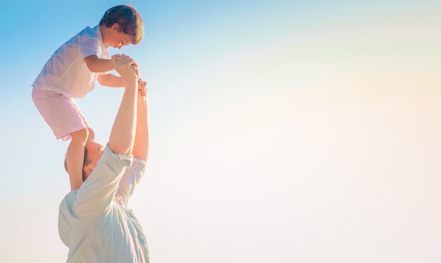 Vater trägt seinen fröhlichen Sohn auf seinen Schultern mit dem hellen Himmel