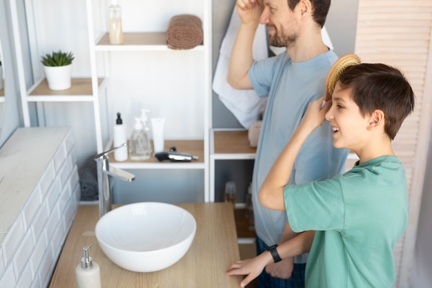 Kostenloses Foto vater und kind des hohen winkels, die haare bürsten