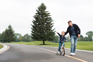 Vater und kind spielen im park mit dem fahrrad