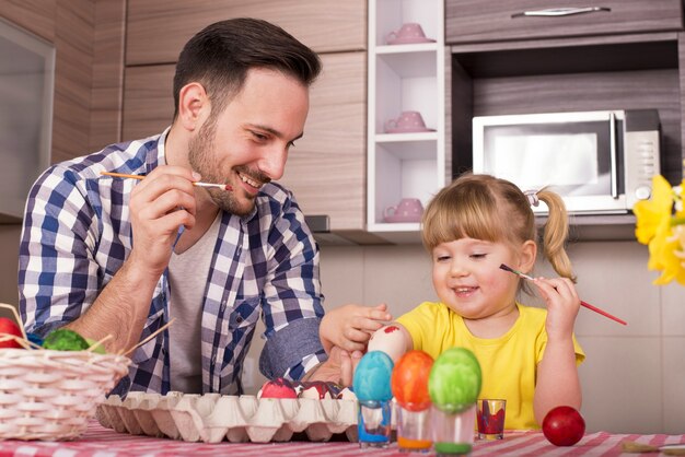 Vater und sein kleines Kind malen die Ostereier