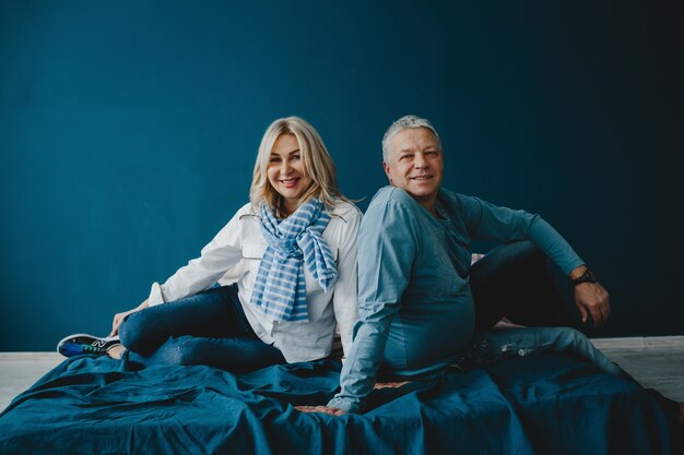 Vater und seine erwachsene Tochter sitzen zusammen auf einem blauen Bett