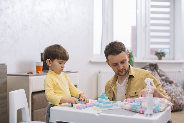 Vater und Sohn bauen drinnen Spielzeug aus Legostücken