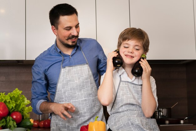 Vater und Sohn des niedrigen Winkels, die mit Gemüse spielen