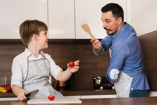Vater und Sohn, die in der Küche beim Kochen spielen