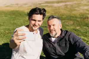 Kostenloses Foto vater und sohn, die selfie am strand nehmen