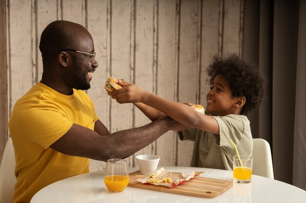 Vater und Sohn essen zusammen zu Mittag und genießen Burger und Pommes