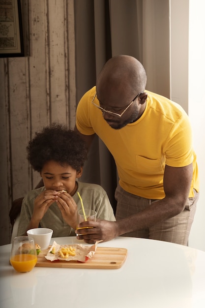 Kostenloses Foto vater und sohn essen zusammen zu mittag und genießen burger und pommes