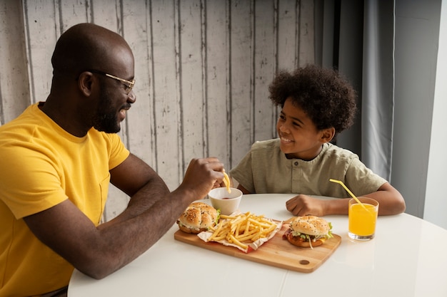 Vater und Sohn genießen gemeinsam Burger und Pommes zu Hause