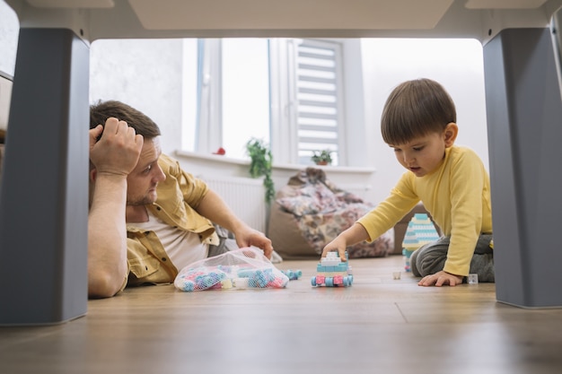 Vater und Sohn im Wohnzimmer unter dem Tisch niedrige Sicht