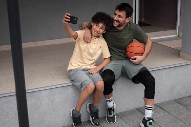 Vater und Sohn machen Selfie im Hinterhof, während sie Basketball spielen