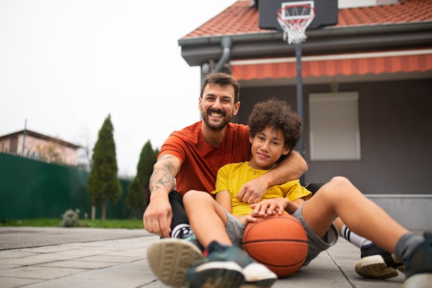 Vater und Sohn spielen gemeinsam Basketball im Hinterhof