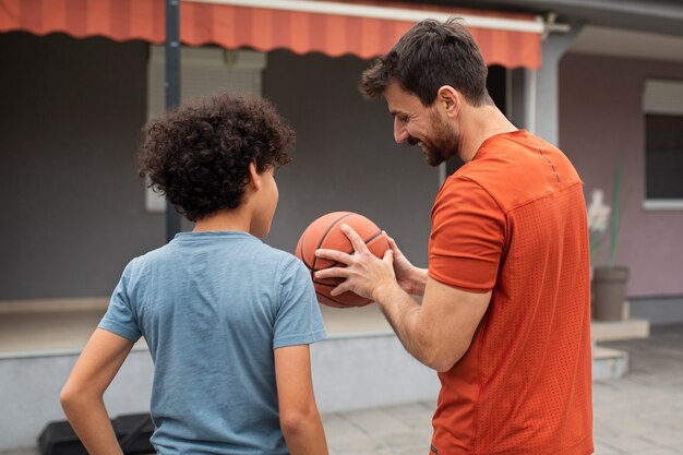 Vater und Sohn spielen gemeinsam Basketball im Hinterhof