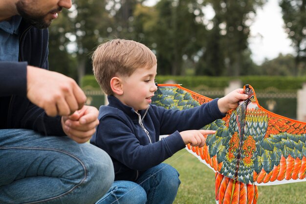 Vater und Sohn spielen mit Drachen im Park