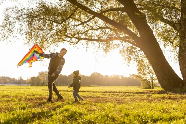 Vater und Sohn spielen mit einem Drachen im Park