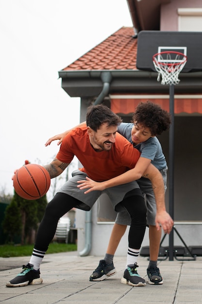 Vater und Sohn spielen zu Hause im Hinterhof zusammen Basketball