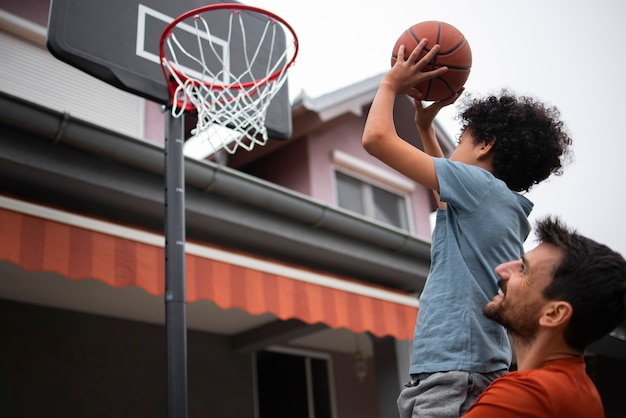 Vater und Sohn spielen zu Hause im Hinterhof zusammen Basketball