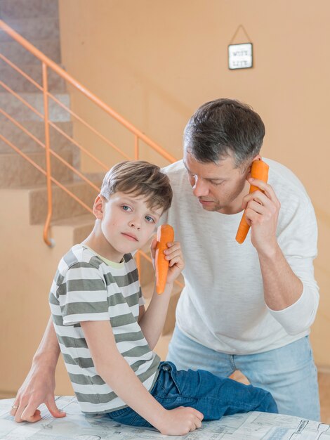 Vater und Sohn unterhalten sich über Karotten-Telefone