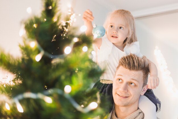 Vater und Tochter, die beleuchteten Weihnachtsbaum berühren