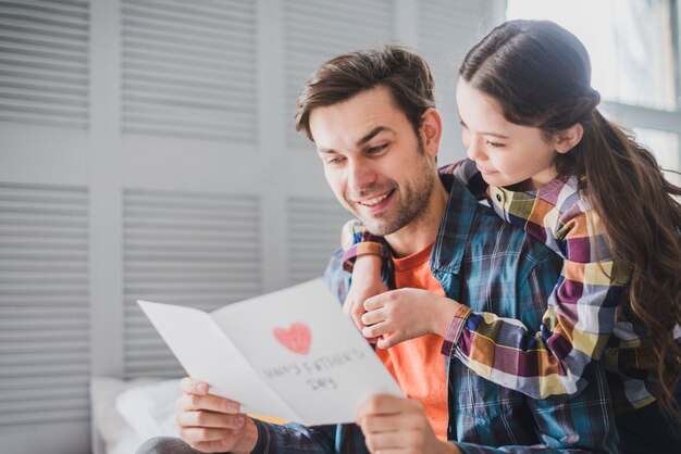 Vater und Tochter, die gezeichnete Handkarte am Vatertag betrachten