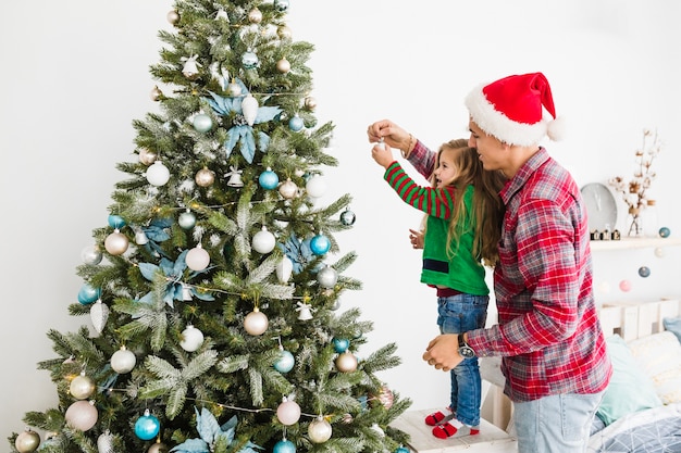 Vater und Tochter, die zusammen Weihnachtsbaum verzieren