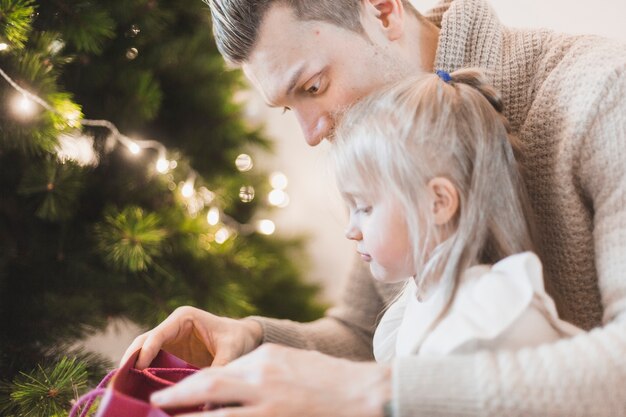 Vater und Tochter neben beleuchtetem Weihnachtsbaum