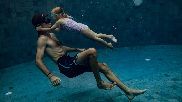 Vater und Tochter schwimmen zusammen im Pool