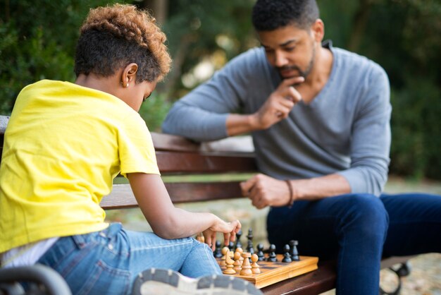 Vater und Tochter spielen Schach auf der Bank im Stadtpark