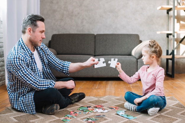 Kostenloses Foto vater- und tochterhand, die puzzlestück hält