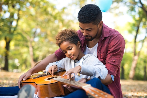 Vater verbringt Zeit mit seiner Tochter und spielt Gitarre