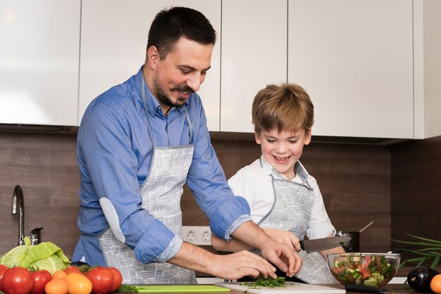 Vati und Sohn des niedrigen Winkels, die Gemüse schneiden