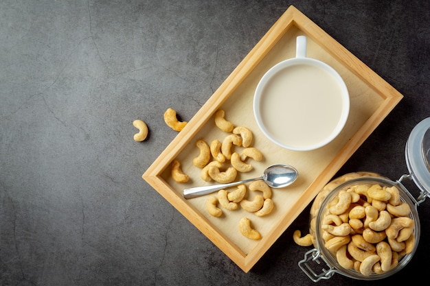 Vegane cashewmilch im glas mit cashewkernen auf dunklem hintergrund