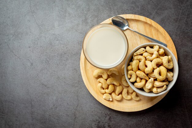 Vegane Cashewmilch im Glas mit Cashewkernen auf dunklem Hintergrund