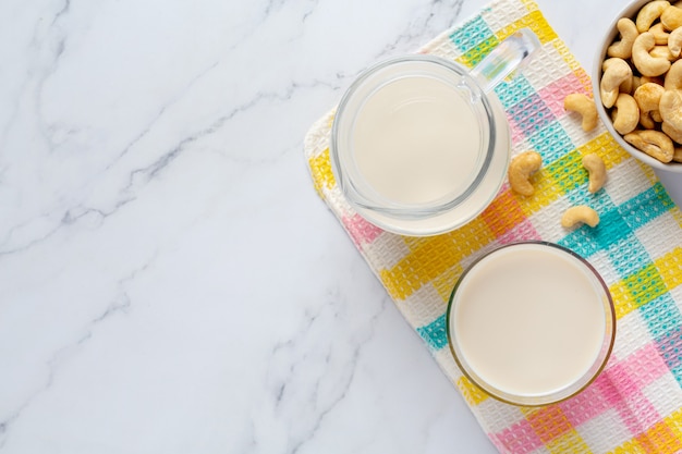 Vegane Cashewmilch im Glas mit Cashewkernen auf Marmorhintergrund