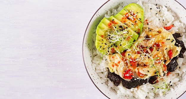 Veganer Salat mit Reis, eingelegtem Kimchi-Kohl, Avocado, Nori und Sesam auf Schüssel.