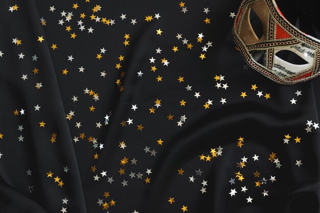 Venezianische Maske auf einem schwarzen Stoff mit Stern Konfetti