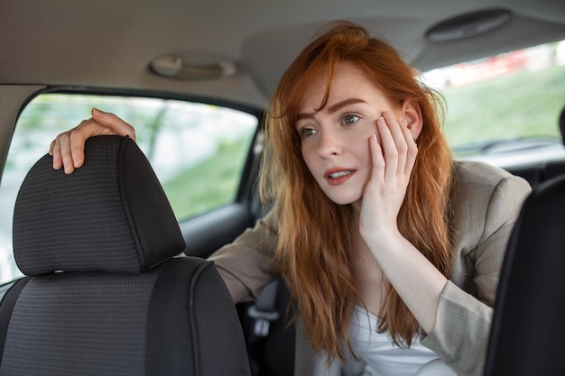 Verängstigte Frau, die die Hand auf dem Kopf hält, während sie im Auto auf verschwommenem Vordergrund fährt